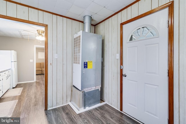 entrance foyer with wood-type flooring, wooden walls, ornamental molding, and ceiling fan