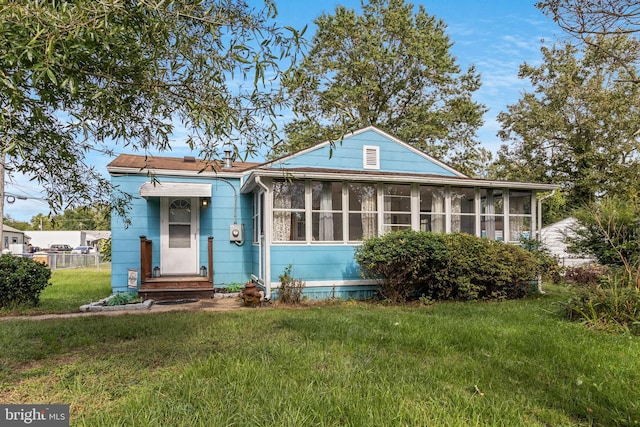 view of front facade with a sunroom and a front lawn