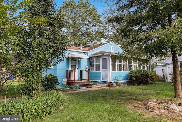 bungalow-style home with a sunroom and a front yard