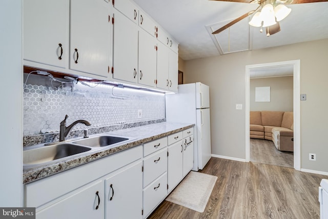 kitchen with light wood-type flooring, sink, tasteful backsplash, and white cabinetry