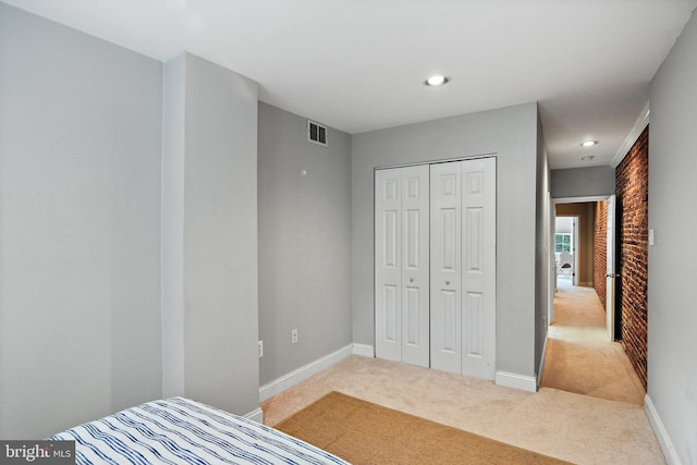 carpeted bedroom featuring brick wall and a closet