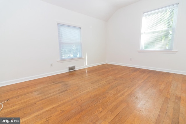 empty room with light hardwood / wood-style floors, vaulted ceiling, and plenty of natural light