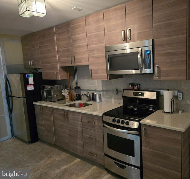 kitchen featuring light tile patterned floors, sink, appliances with stainless steel finishes, and tasteful backsplash