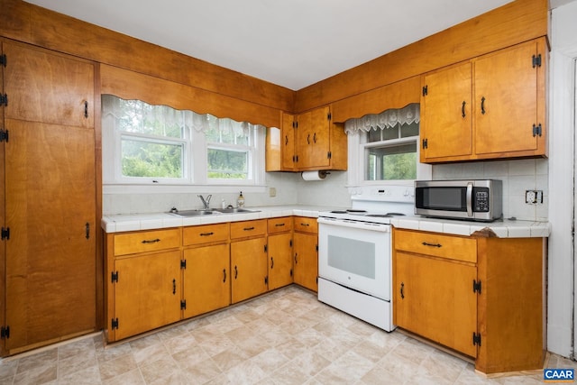 kitchen featuring backsplash, sink, white range with electric stovetop, and plenty of natural light