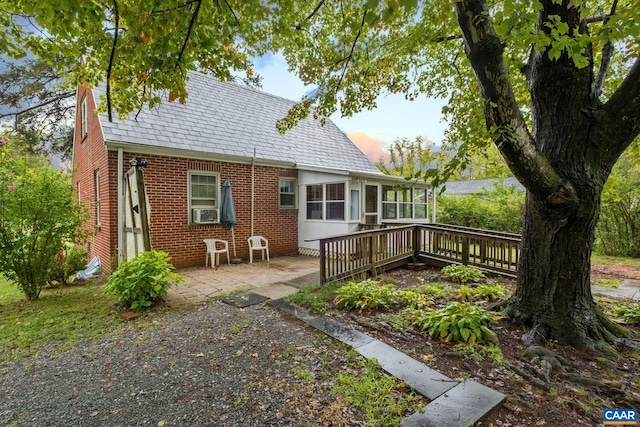 rear view of property with a wooden deck, cooling unit, and a patio