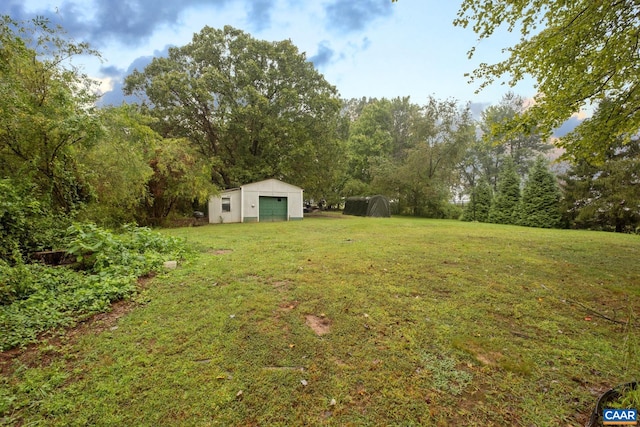 view of yard with a garage and an outbuilding