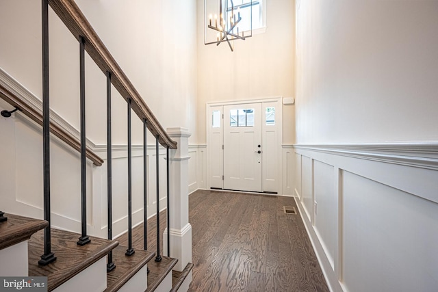 entryway with dark wood-type flooring and an inviting chandelier