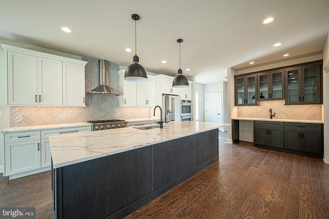 kitchen featuring sink, stainless steel appliances, white cabinets, decorative light fixtures, and wall chimney exhaust hood