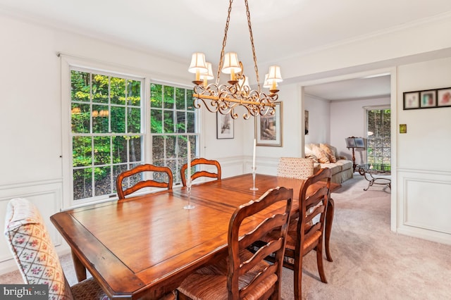 dining room featuring ornamental molding, a notable chandelier, and light colored carpet