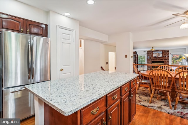 kitchen with stainless steel fridge, a kitchen island, a fireplace, and dark hardwood / wood-style floors