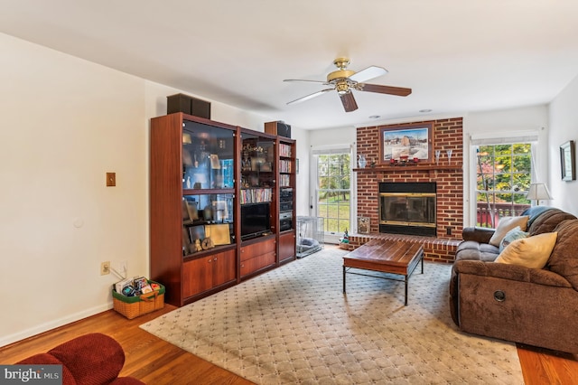 living room featuring a brick fireplace, light hardwood / wood-style flooring, and ceiling fan