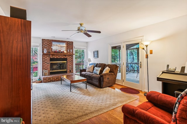 living room featuring ceiling fan, a brick fireplace, plenty of natural light, and hardwood / wood-style floors