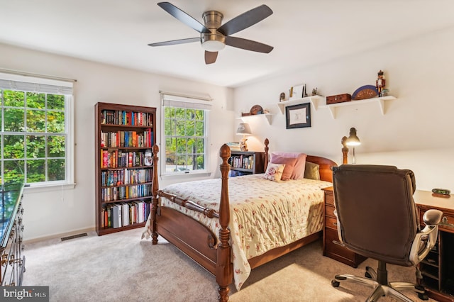 bedroom with ceiling fan, light colored carpet, and multiple windows