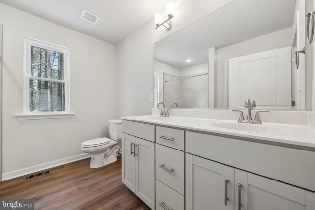 bathroom featuring vanity, toilet, wood-type flooring, and a shower