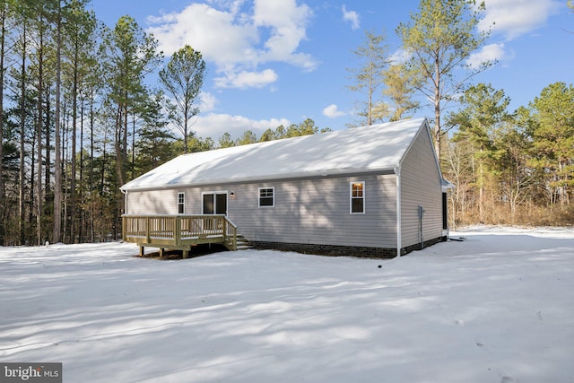 snow covered house featuring a wooden deck