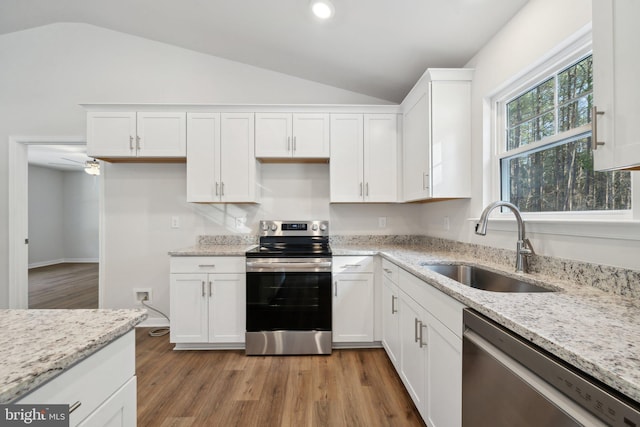 kitchen with white cabinets, stainless steel appliances, lofted ceiling, and sink