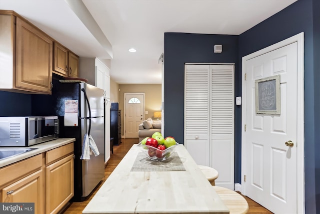 kitchen with wood-type flooring, black fridge, and a center island