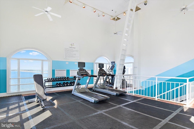 gym featuring a high ceiling, a water view, and ceiling fan