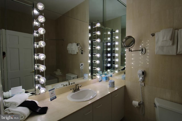 bathroom featuring tile walls, vanity, and toilet