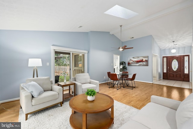 living room featuring ceiling fan, light wood-type flooring, and lofted ceiling with skylight