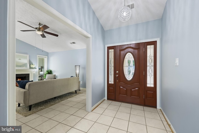 entrance foyer with ceiling fan with notable chandelier, lofted ceiling, and light tile patterned floors