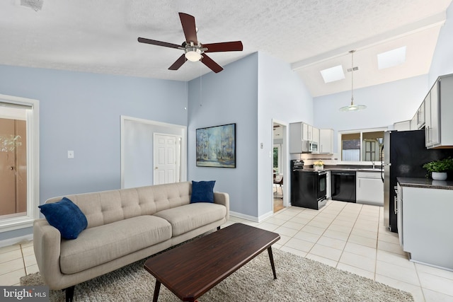 tiled living room featuring high vaulted ceiling, a skylight, ceiling fan, and a textured ceiling