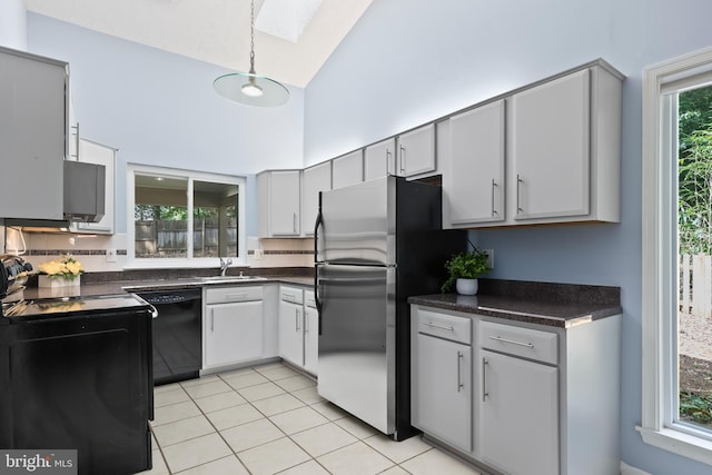 kitchen featuring stainless steel refrigerator, black dishwasher, gray cabinetry, and a skylight