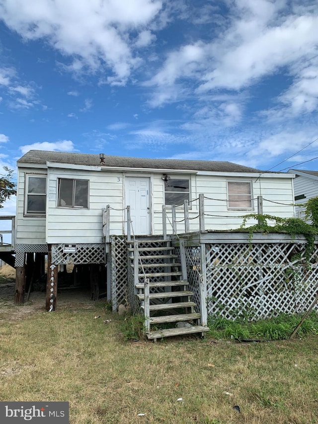 back of property with a deck and a lawn