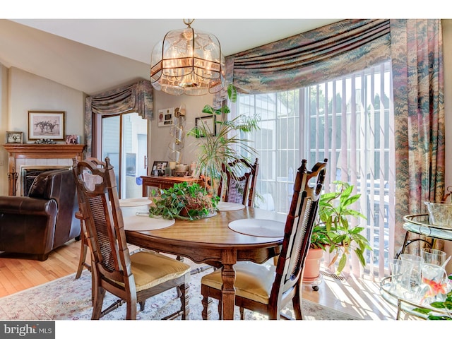 dining area featuring vaulted ceiling, an inviting chandelier, plenty of natural light, and light hardwood / wood-style floors