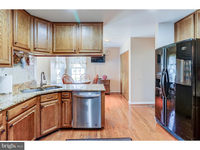 kitchen featuring sink, kitchen peninsula, light hardwood / wood-style flooring, black refrigerator with ice dispenser, and stainless steel dishwasher