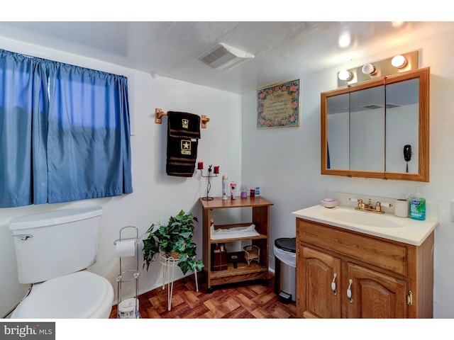 bathroom featuring parquet floors, vanity, and toilet