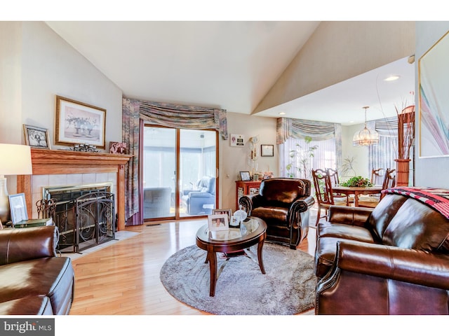 living room featuring a healthy amount of sunlight, a fireplace, a chandelier, and hardwood / wood-style flooring