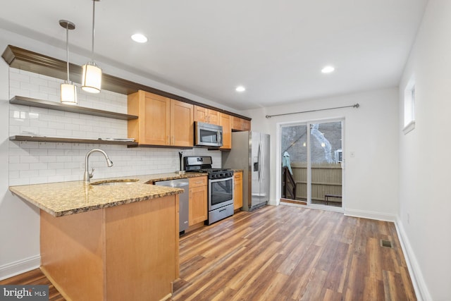 kitchen featuring pendant lighting, sink, kitchen peninsula, hardwood / wood-style flooring, and stainless steel appliances