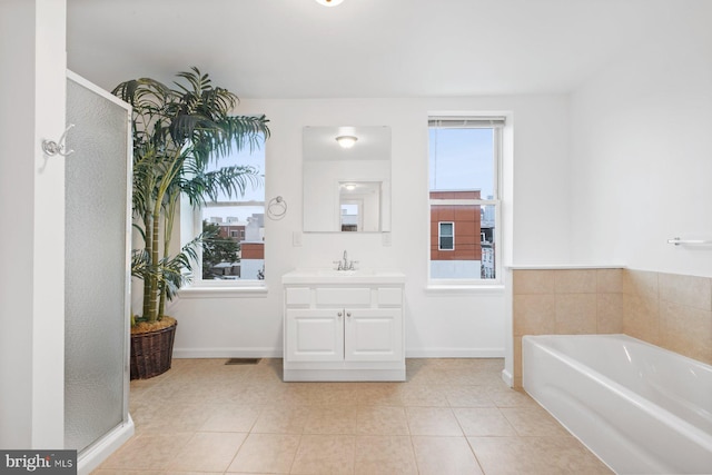 bathroom featuring plus walk in shower, a wealth of natural light, tile patterned flooring, and vanity