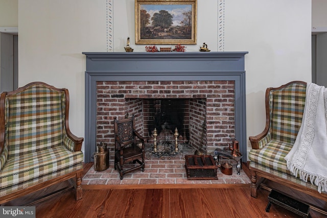 living area with hardwood / wood-style flooring and a brick fireplace