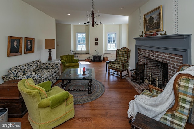 living room with dark wood-type flooring, a notable chandelier, and a fireplace