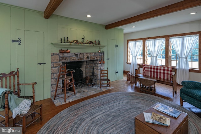 living room featuring beam ceiling, hardwood / wood-style floors, and a fireplace