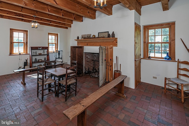 dining space featuring beam ceiling, a fireplace, and an inviting chandelier