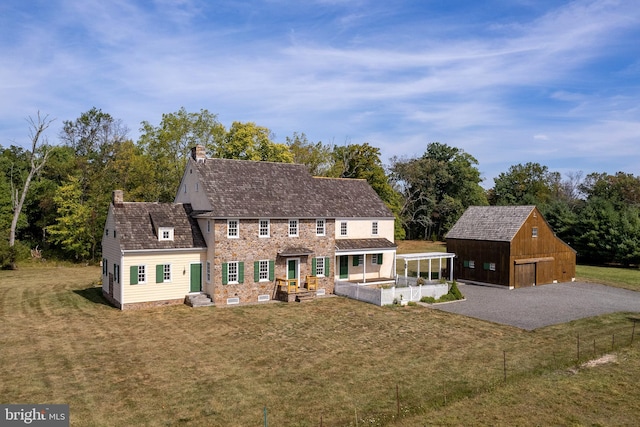 view of front of home with an outdoor structure, a garage, and a front lawn