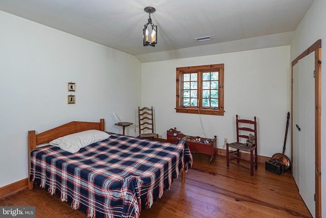 bedroom featuring a notable chandelier and hardwood / wood-style flooring