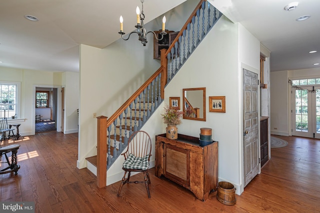 stairs featuring a wealth of natural light, an inviting chandelier, and hardwood / wood-style floors