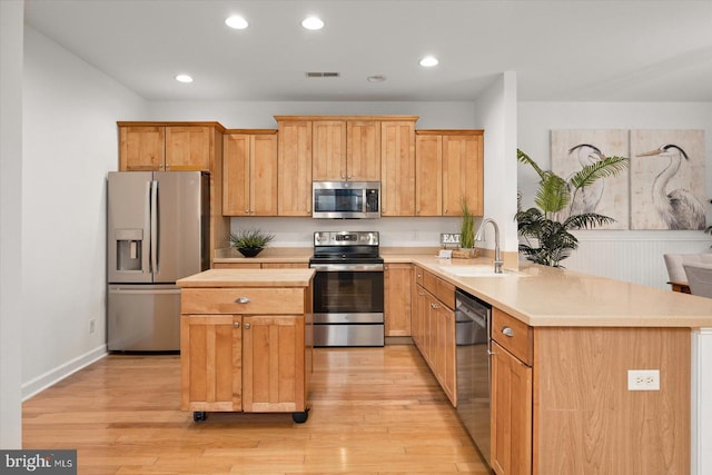 kitchen featuring sink, appliances with stainless steel finishes, light hardwood / wood-style floors, and kitchen peninsula