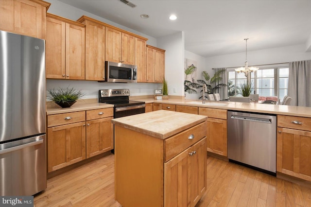 kitchen with light hardwood / wood-style floors, appliances with stainless steel finishes, an inviting chandelier, and a center island