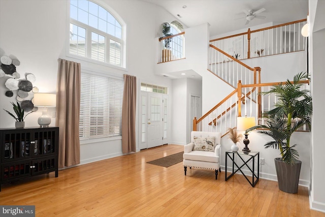 foyer featuring wood-type flooring, a high ceiling, and ceiling fan