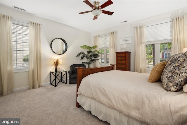 carpeted bedroom featuring multiple windows and ceiling fan