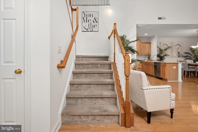 stairway with a notable chandelier, hardwood / wood-style flooring, and sink