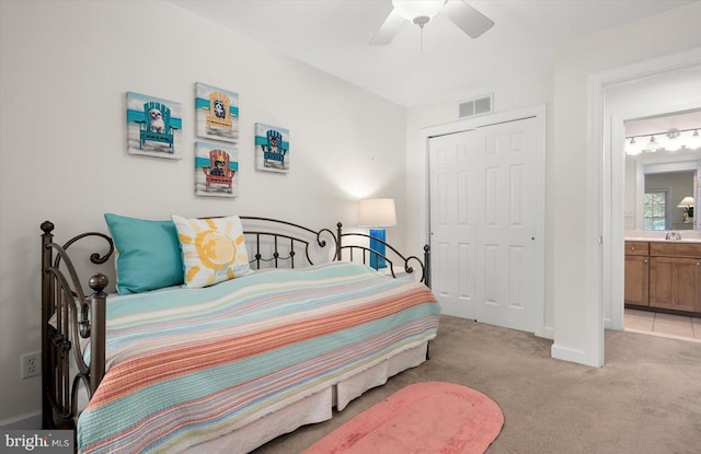 carpeted bedroom with ceiling fan, a closet, connected bathroom, and sink