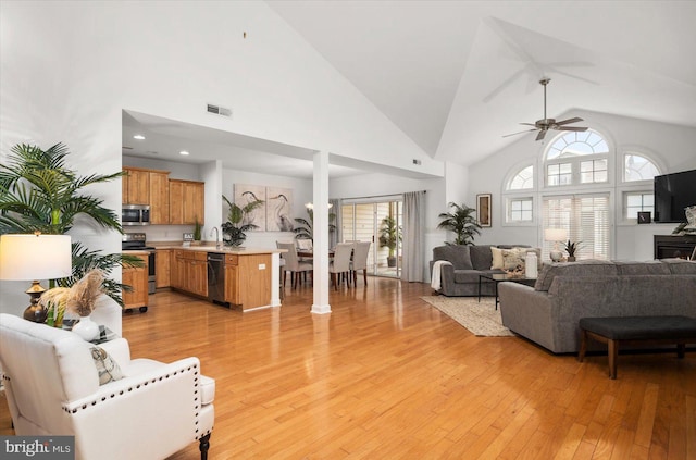 living room with ceiling fan, light wood-type flooring, and a healthy amount of sunlight