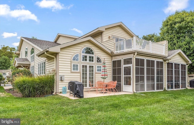 rear view of property with a sunroom, a patio, a balcony, and a lawn