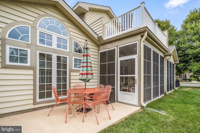 back of house with a yard, a balcony, a patio area, and a sunroom